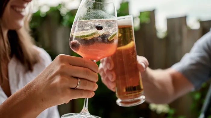 Freunde stoßen mit Cocktail und Bier auf einer Außenterrasse an